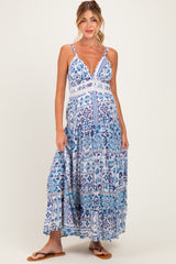 woman wearing a blue and white patterned maternity maxi dress with a deep v-neck and adjustable straps, showcasing her baby bump