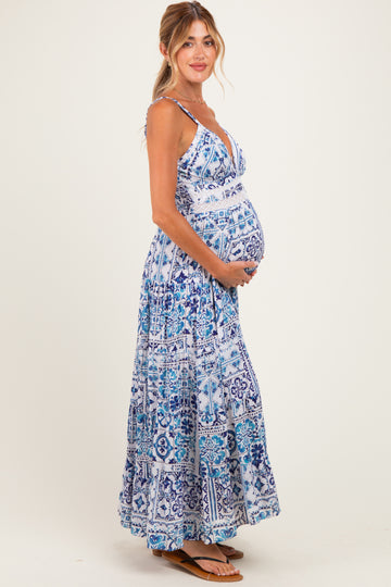 woman wearing a blue and white patterned maternity dress and holding her baby bump