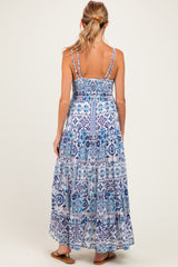 woman wearing a blue printed maternity maxi dress with spaghetti straps and tiered ruffle details, showing the back view