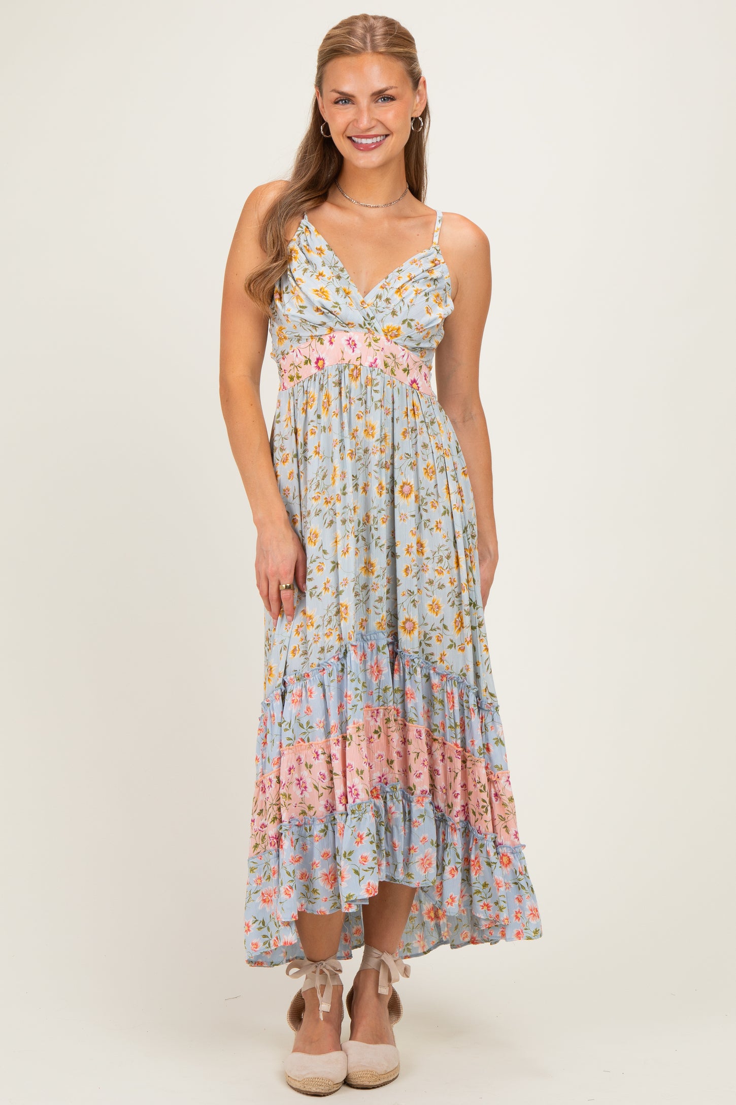 woman wearing a light blue floral maxi dress with adjustable straps and tiered ruffles at the hem