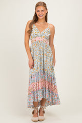woman wearing a light blue floral maxi dress with adjustable straps and tiered ruffles at the hem