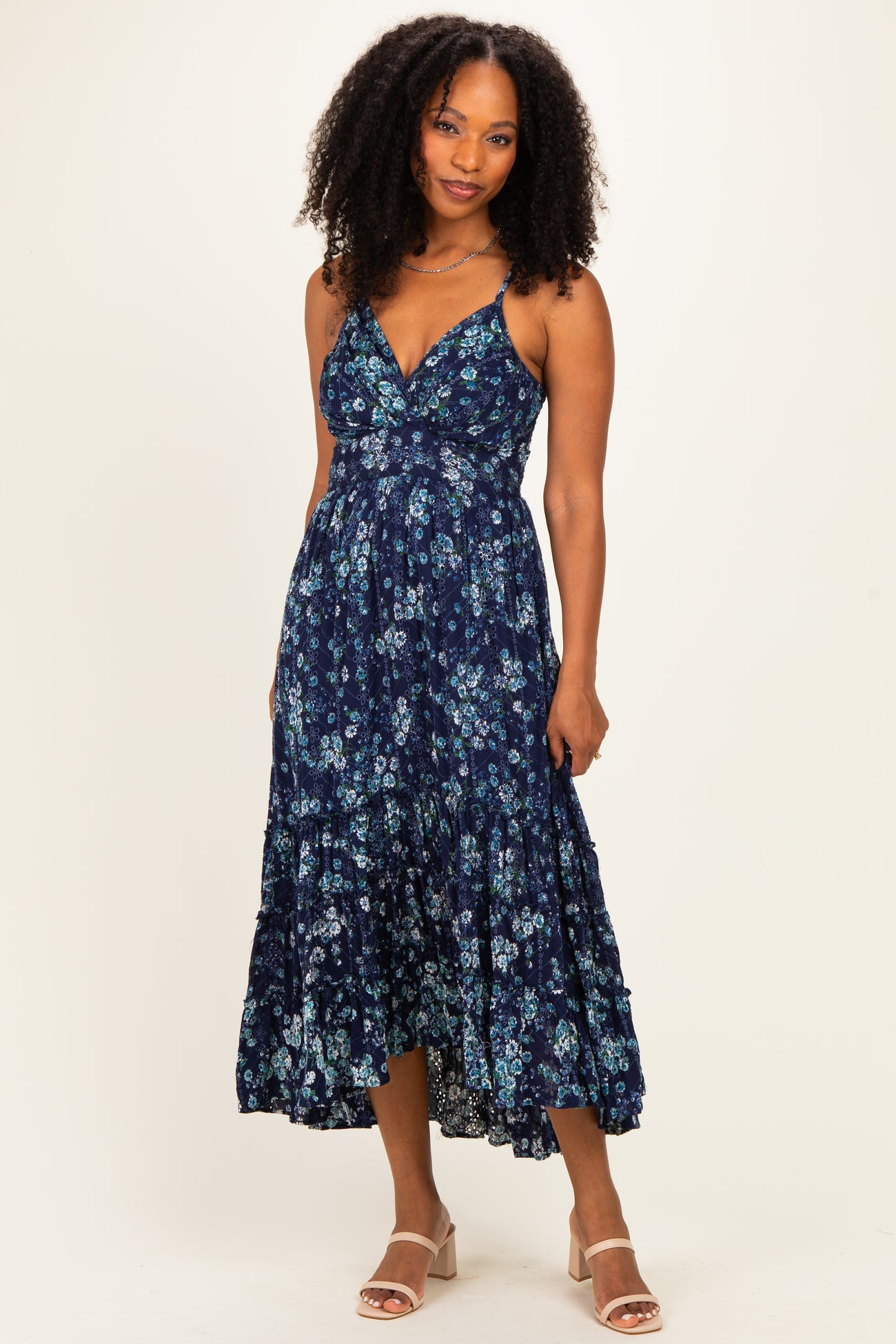 woman wearing a navy blue floral maxi dress with a v-neckline and tiered skirt, standing on a light background
