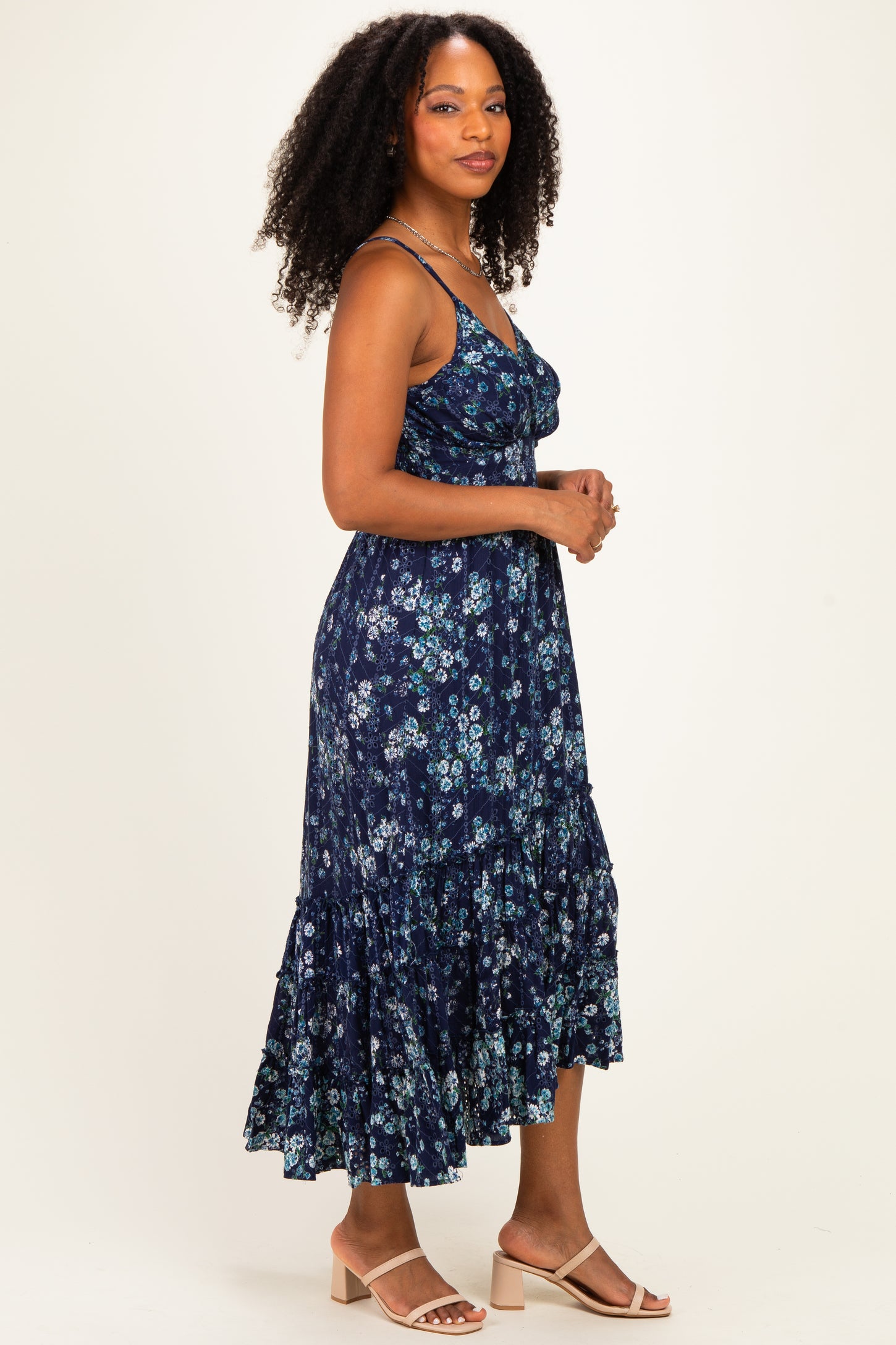 woman wearing a navy blue floral midi dress with spaghetti straps and a tiered hem