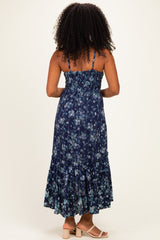 woman wearing a navy blue floral maxi dress with adjustable straps and a tiered ruffle hem