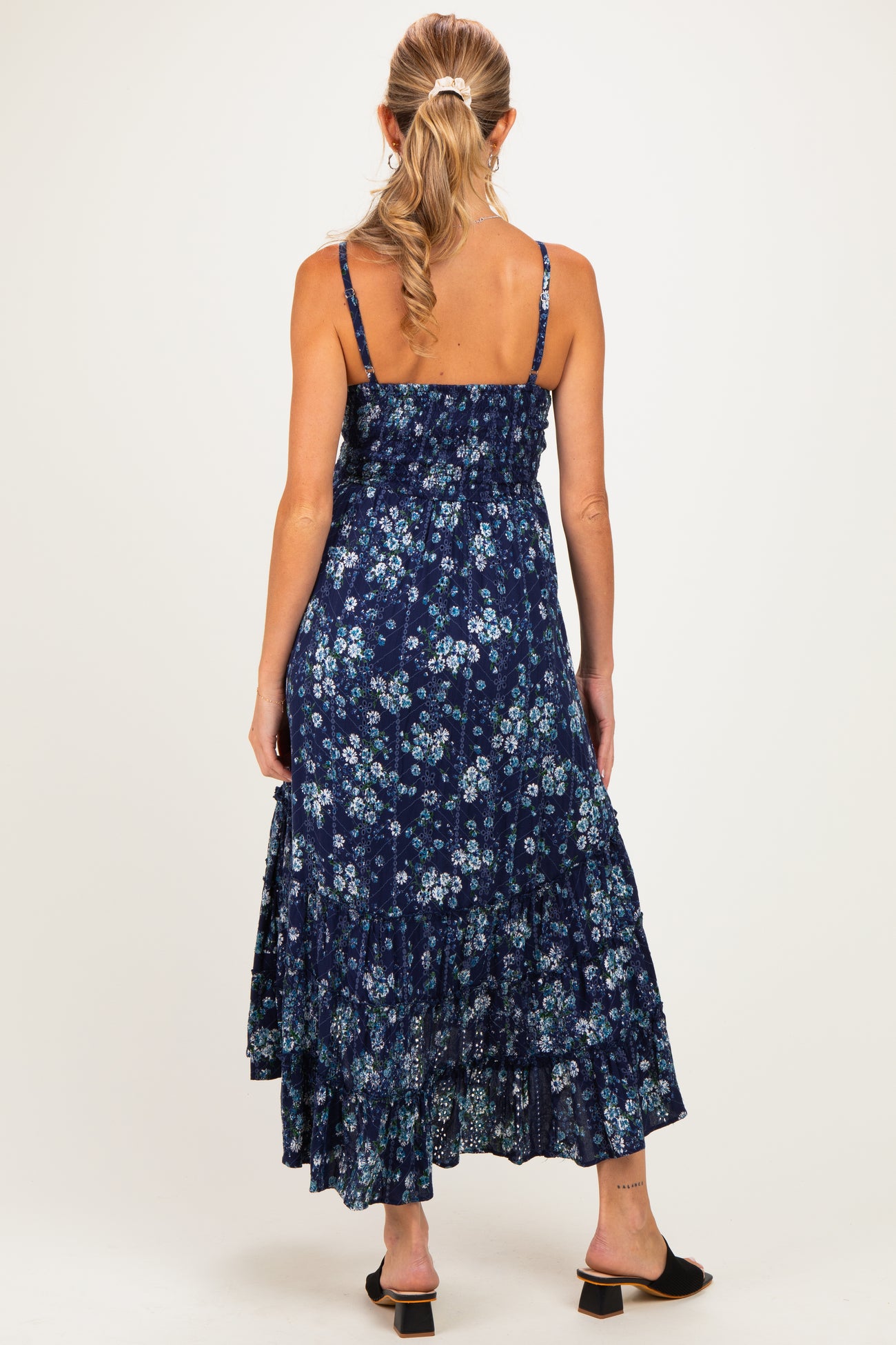 woman wearing a navy blue floral maternity maxi dress with adjustable straps and a tiered skirt