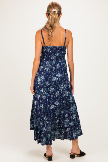 woman wearing a navy blue floral maternity maxi dress with adjustable straps and a tiered skirt