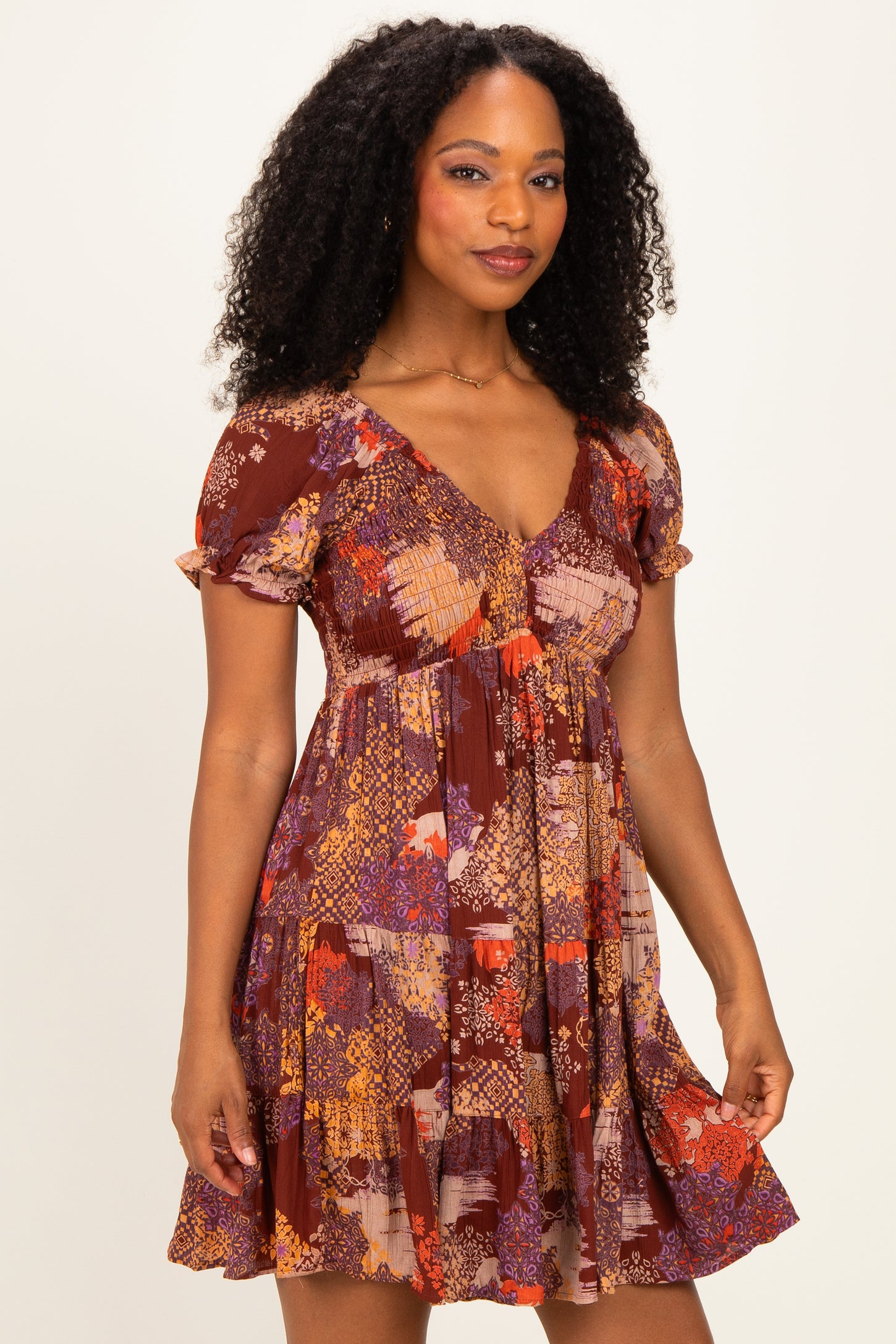 woman wearing a floral patterned short sleeve dress in warm tones with a flared skirt and slightly ruffled sleeves