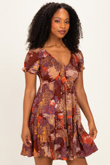 woman wearing a floral patterned short sleeve dress in warm tones with a flared skirt and slightly ruffled sleeves