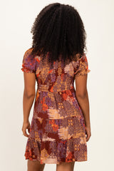 woman wearing a short-sleeve brown patterned dress with a flared skirt and a fitted bodice, seen from the back