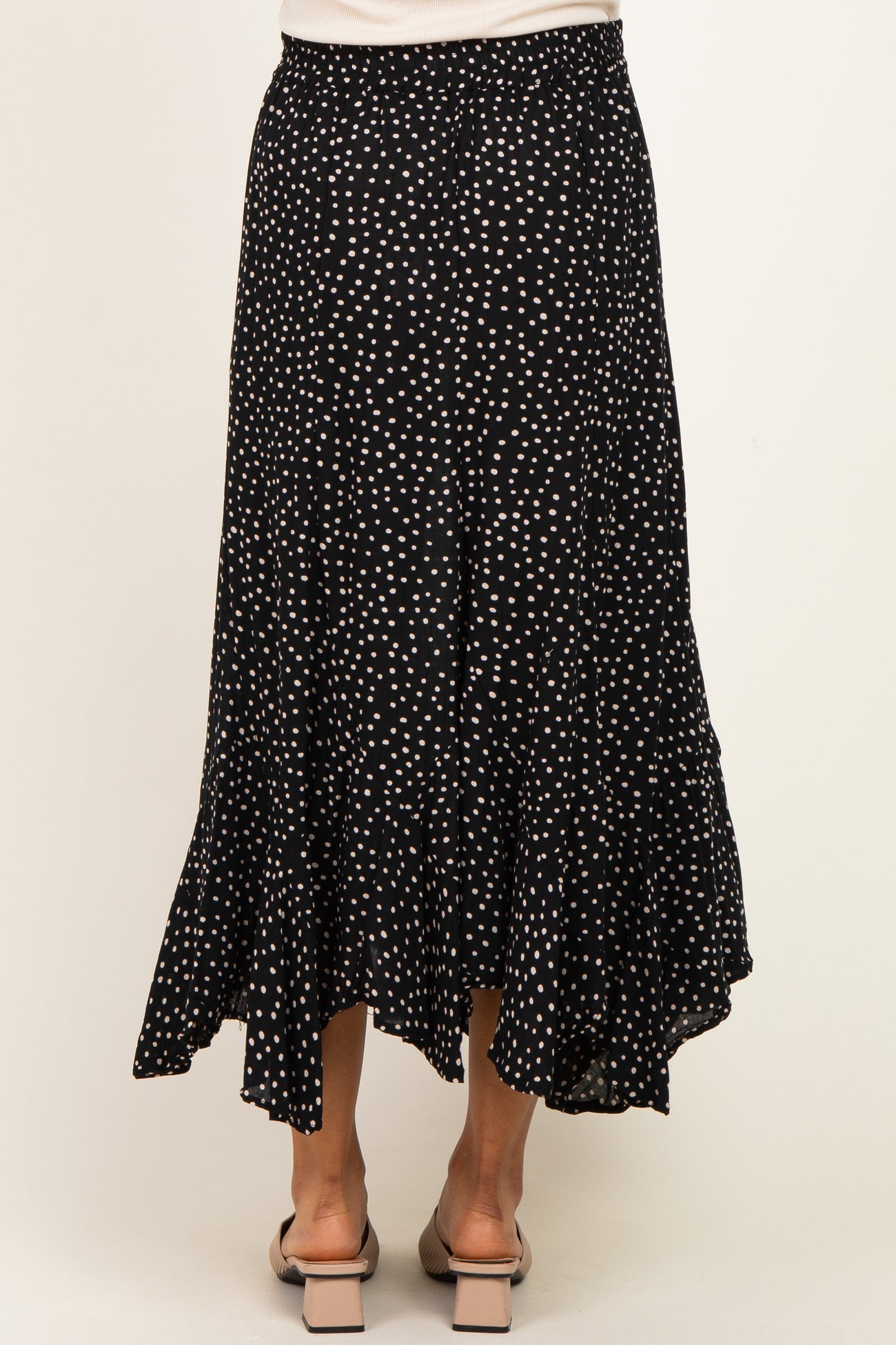 woman wearing a black polka dot maternity maxi skirt with a flared hem and an elastic waistband