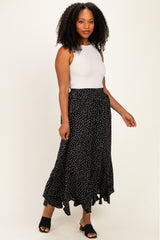 woman wearing a white sleeveless top and a black polka dot maxi skirt with a ruffled hem