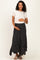 woman wearing a cream short sleeve top and a black polka dot maternity maxi skirt, holding her baby bump