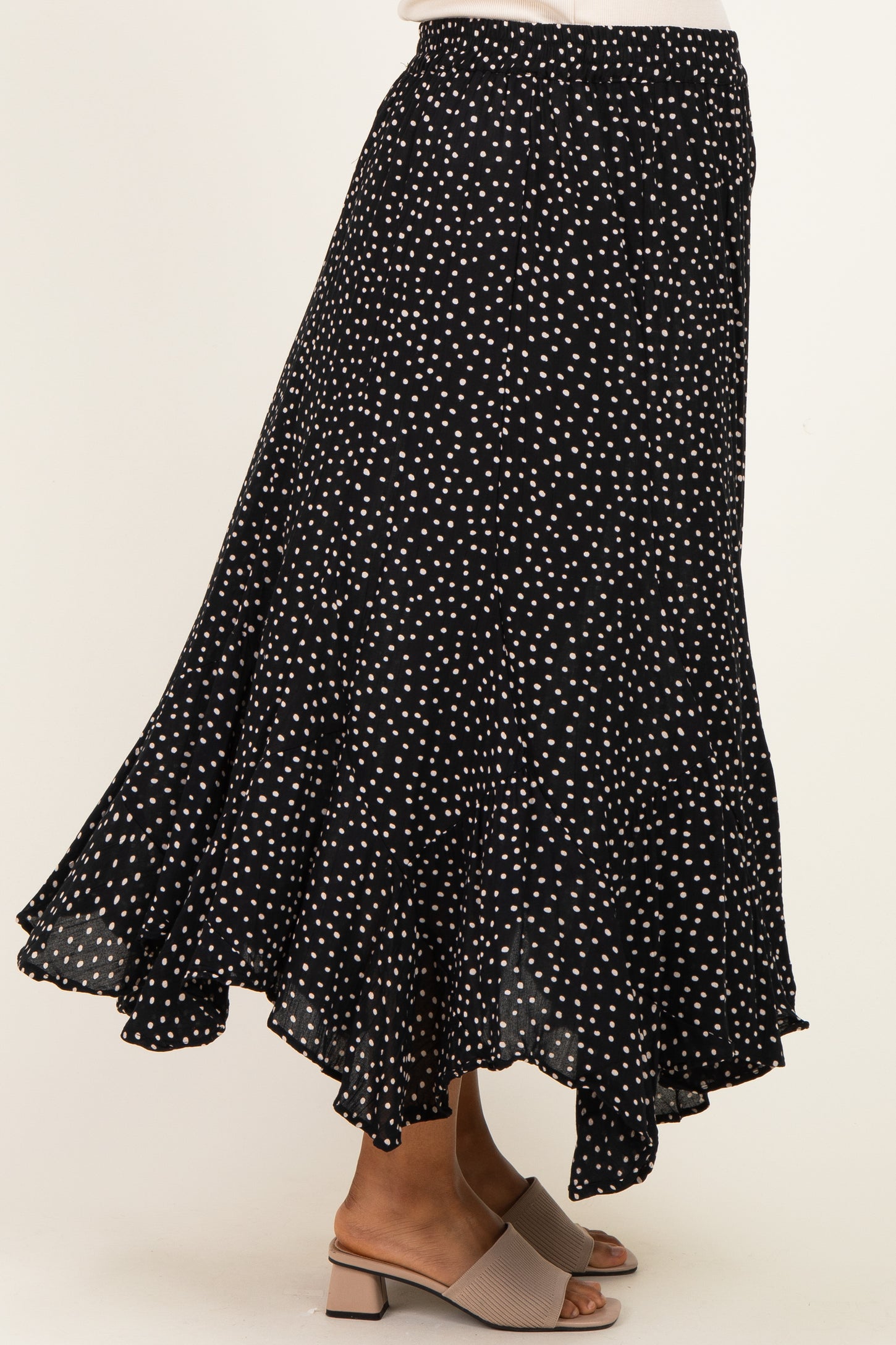 maternity wear black polka dot midi skirt with a flowing ruffle hem, styled with a pair of beige block-heeled sandals