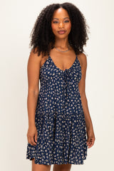 woman wearing a navy blue floral spaghetti strap dress with a tie-front detail and a tiered skirt