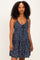 woman wearing a navy blue floral spaghetti strap dress with a tie-front detail and a tiered skirt