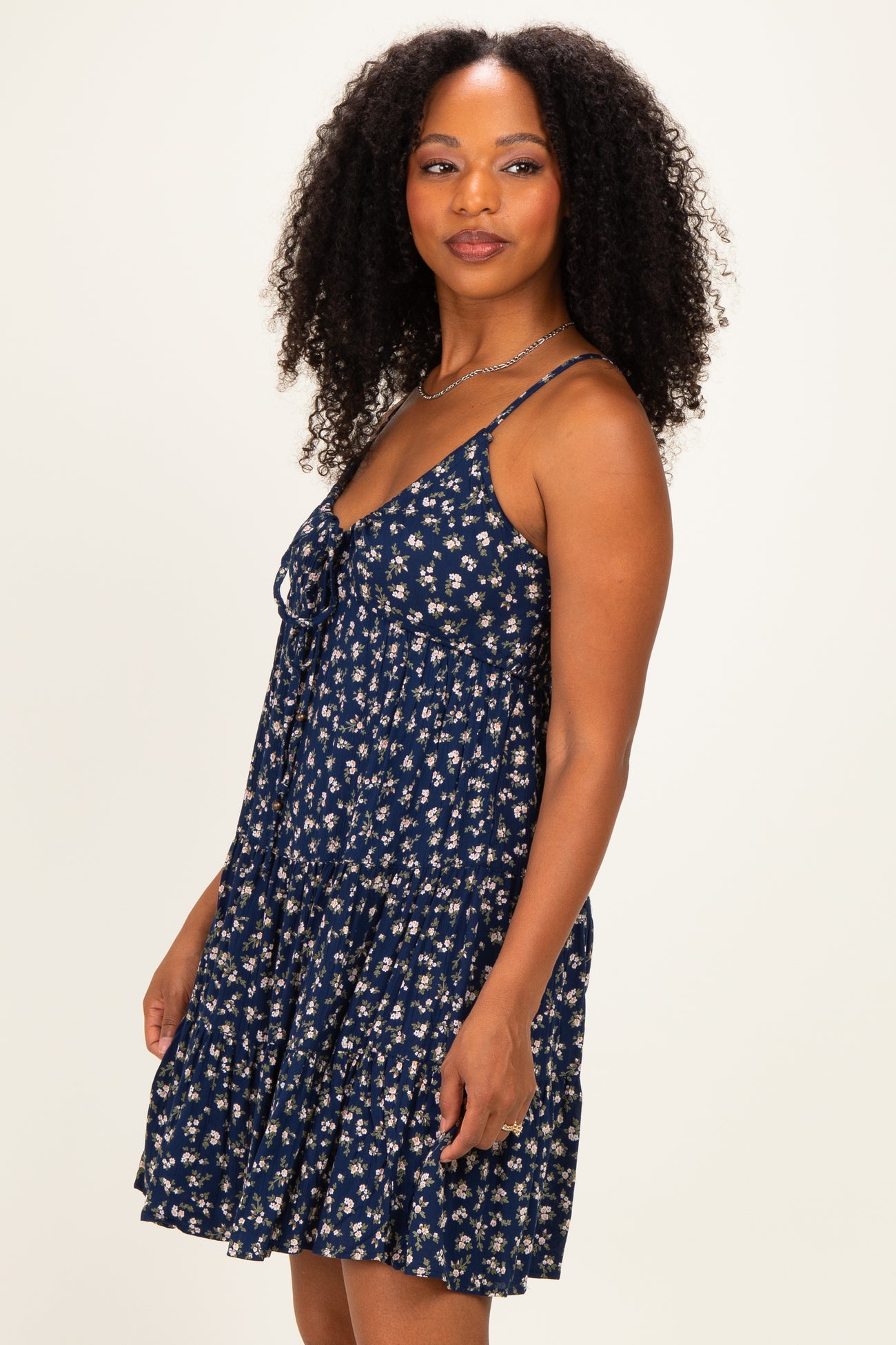 woman wearing a navy blue floral print sundress with adjustable straps and a tiered hemline