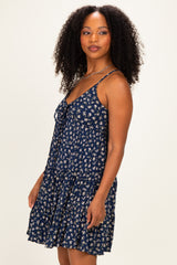 woman wearing a navy blue floral print sundress with adjustable straps and a tiered hemline