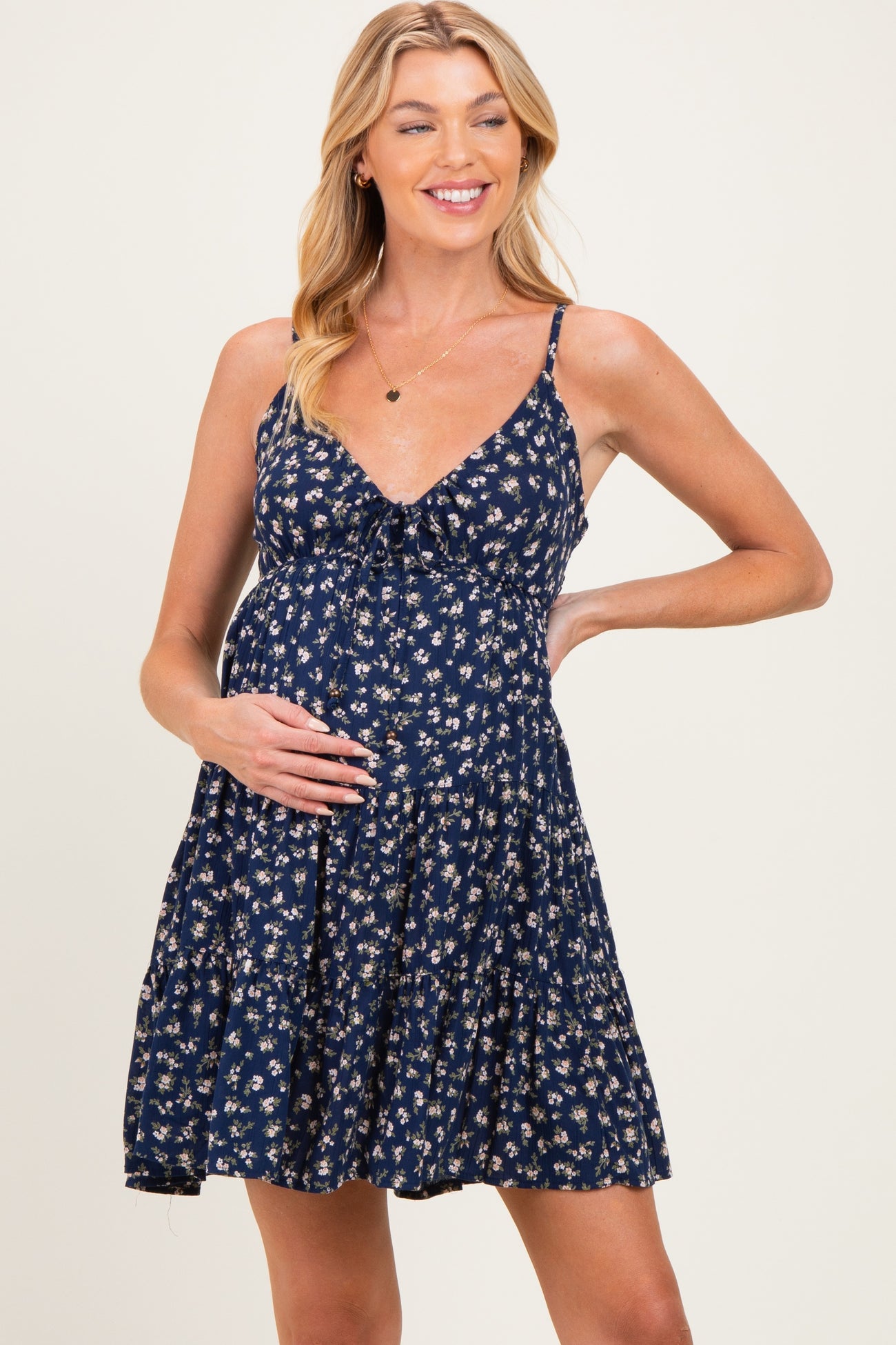 woman wearing a navy blue floral maternity dress and gently cradling her baby bump