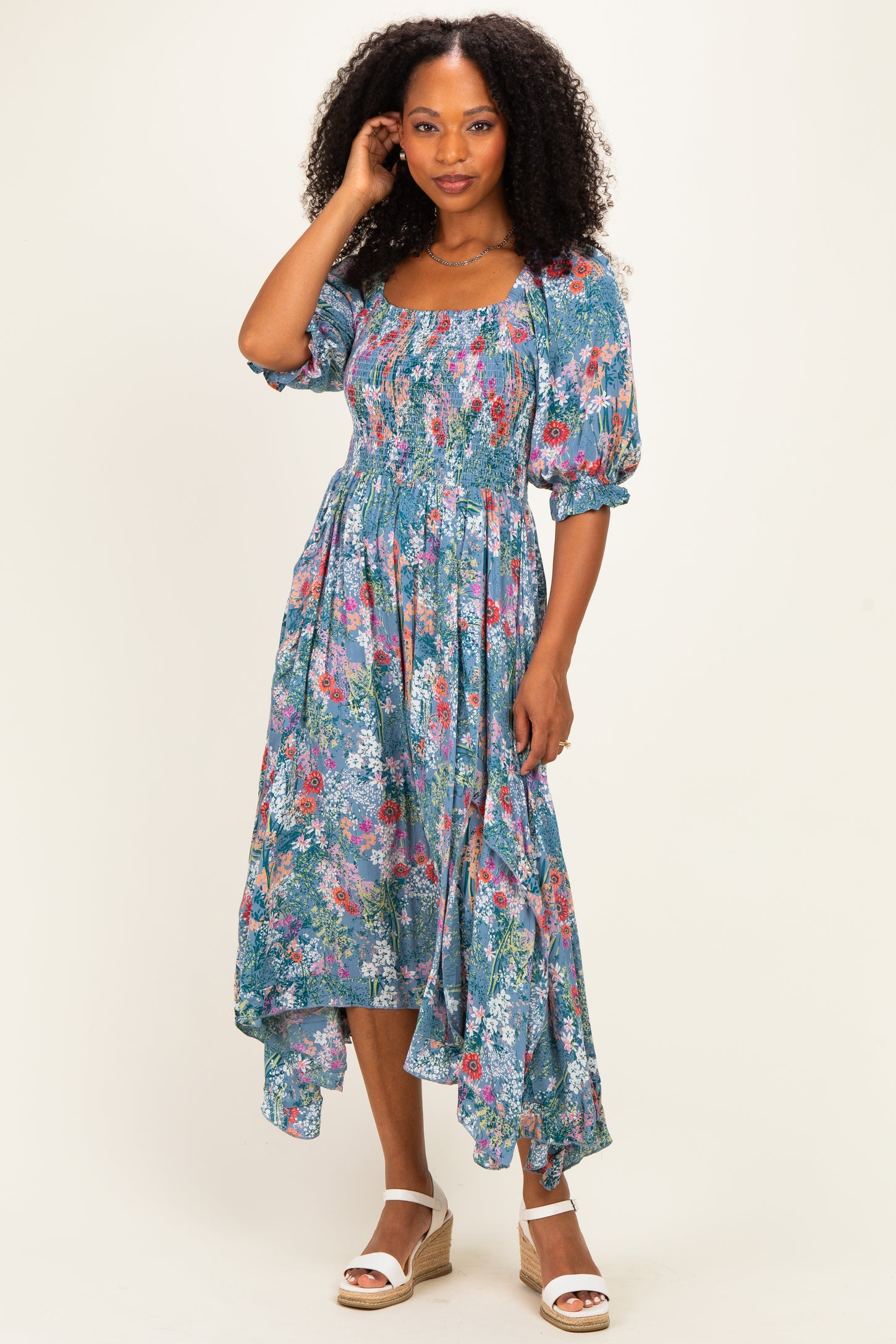 woman wearing a floral print midi dress with puff sleeves and a high-low hemline