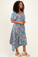 woman wearing a floral print midi dress with puff sleeves and a high-low hemline, paired with wedge sandals