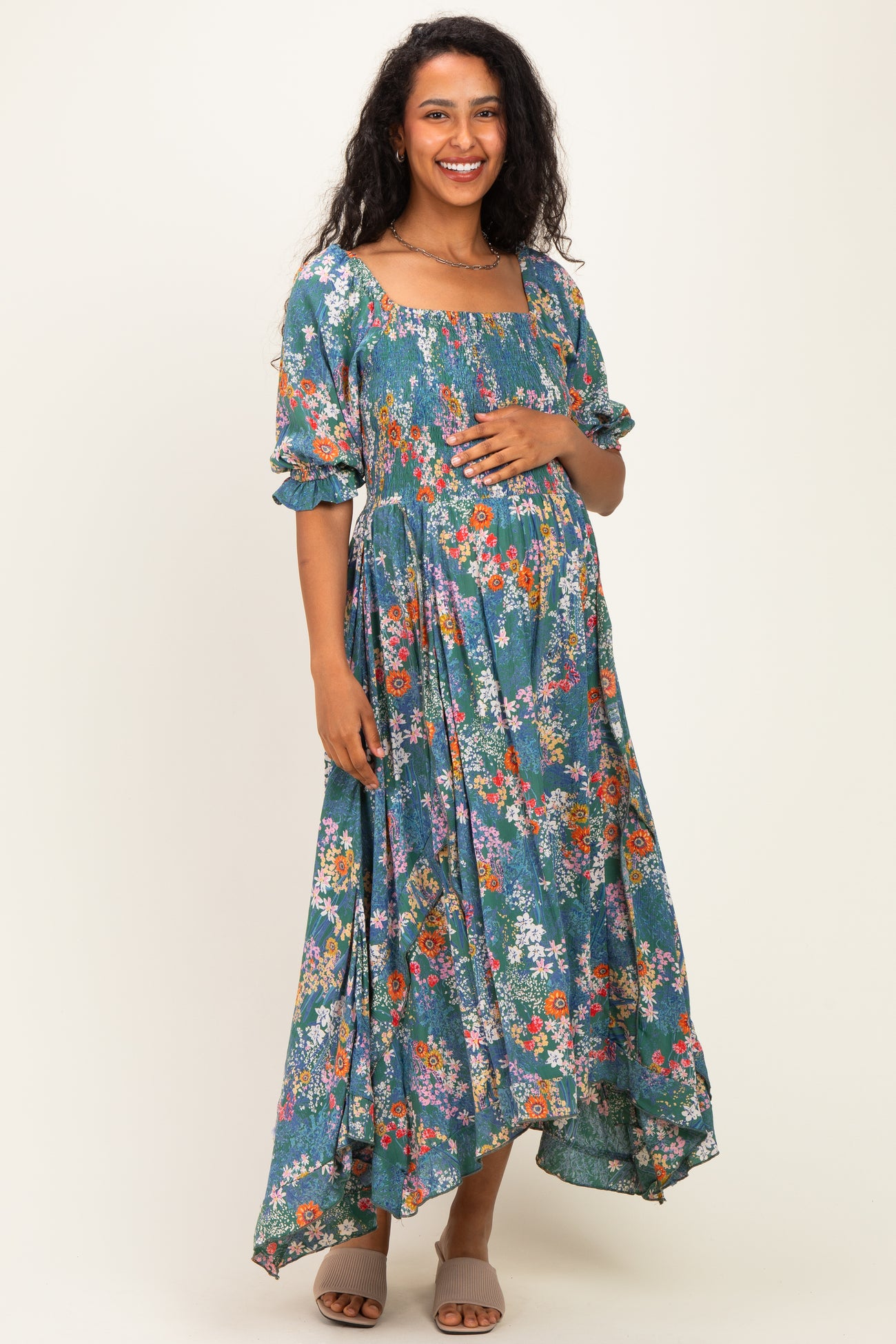 woman wearing a floral maternity maxi dress with a square neckline and puff sleeves, holding her baby bump