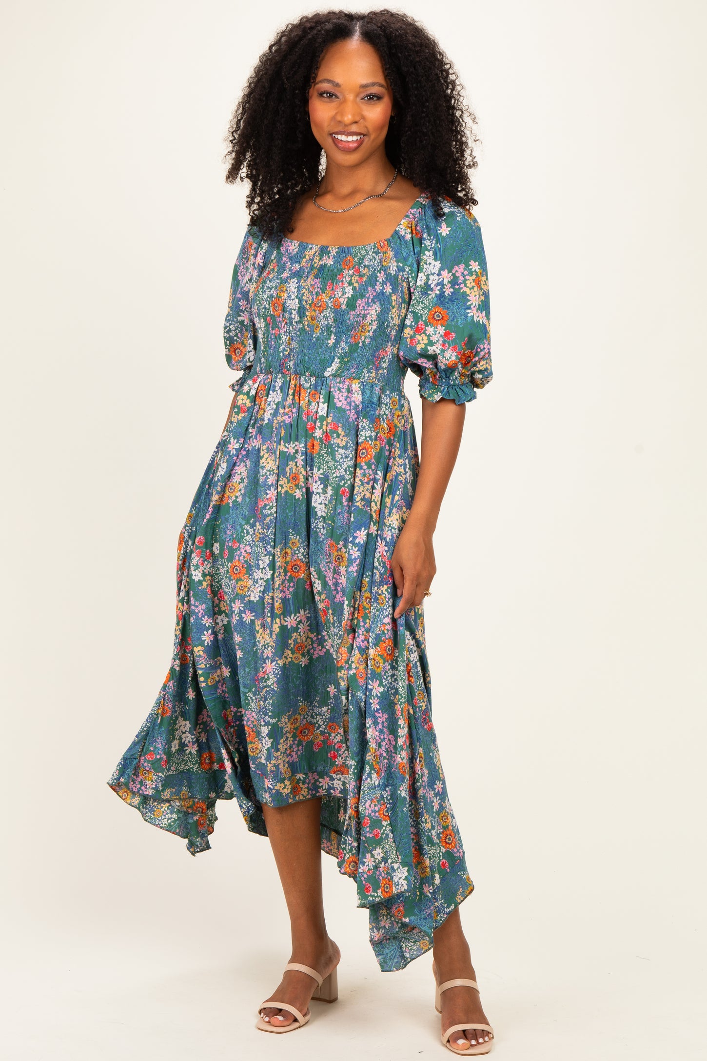 woman wearing a teal floral midi dress with puff sleeves and a high-low hemline