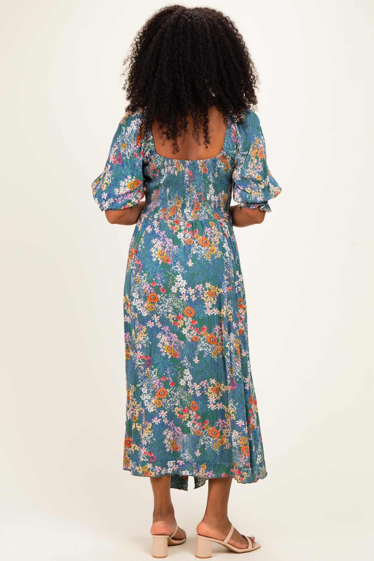 woman wearing a floral print midi dress with puff sleeves and a smocked back, viewed from the back