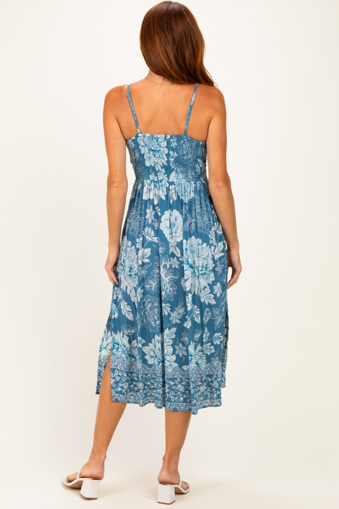 woman wearing a blue floral maxi dress with spaghetti straps, showing the back view and split hem details
