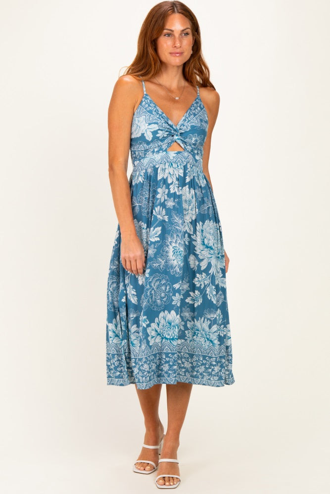 woman wearing a blue floral print midi dress with a twist front detail and spaghetti straps