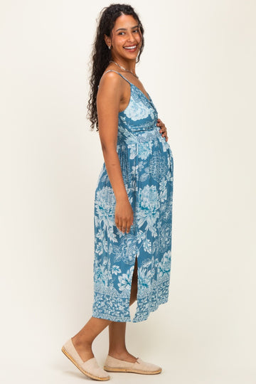 woman wearing a blue floral maternity maxi dress with side slits and holding her baby bump