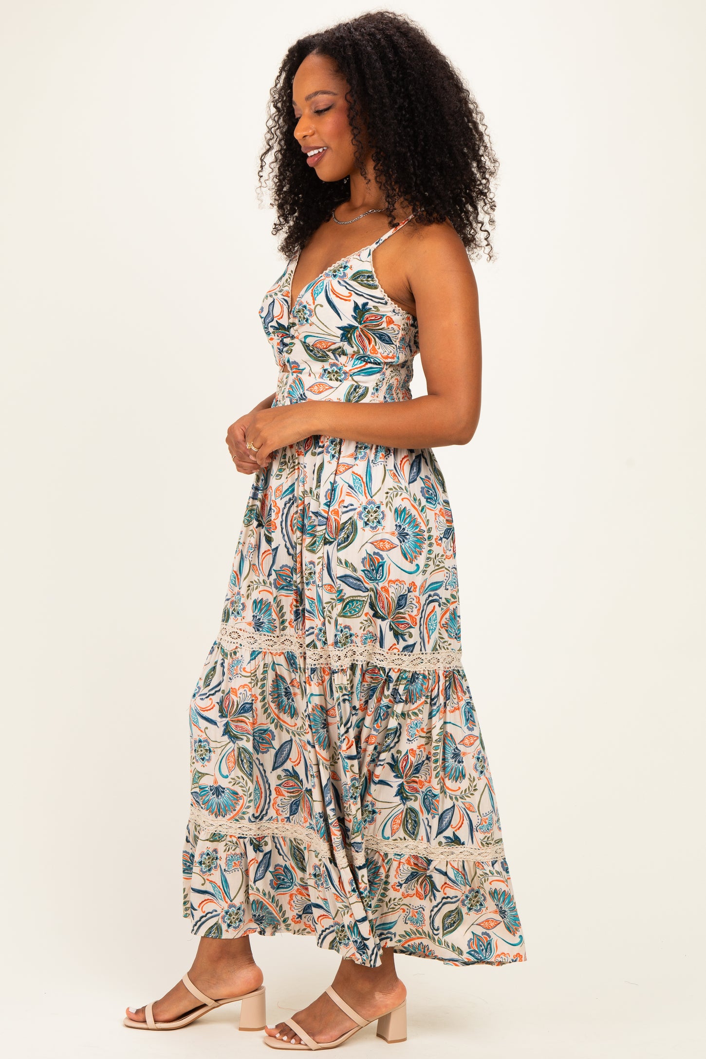 woman wearing a floral print maxi dress with a tiered skirt and spaghetti straps