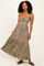 woman wearing a brown floral maxi dress with a front knot and ruffled hem, standing confidently