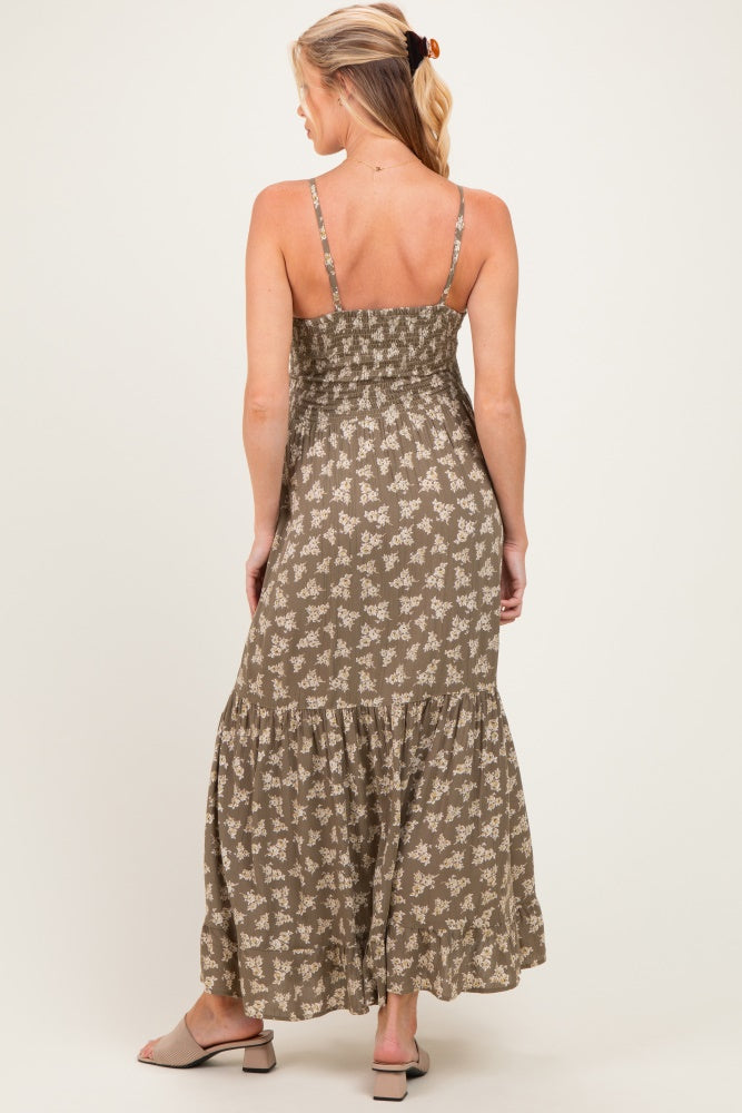 woman wearing a khaki floral print maternity maxi dress with a smocked bodice and tiered skirt, showing a baby bump