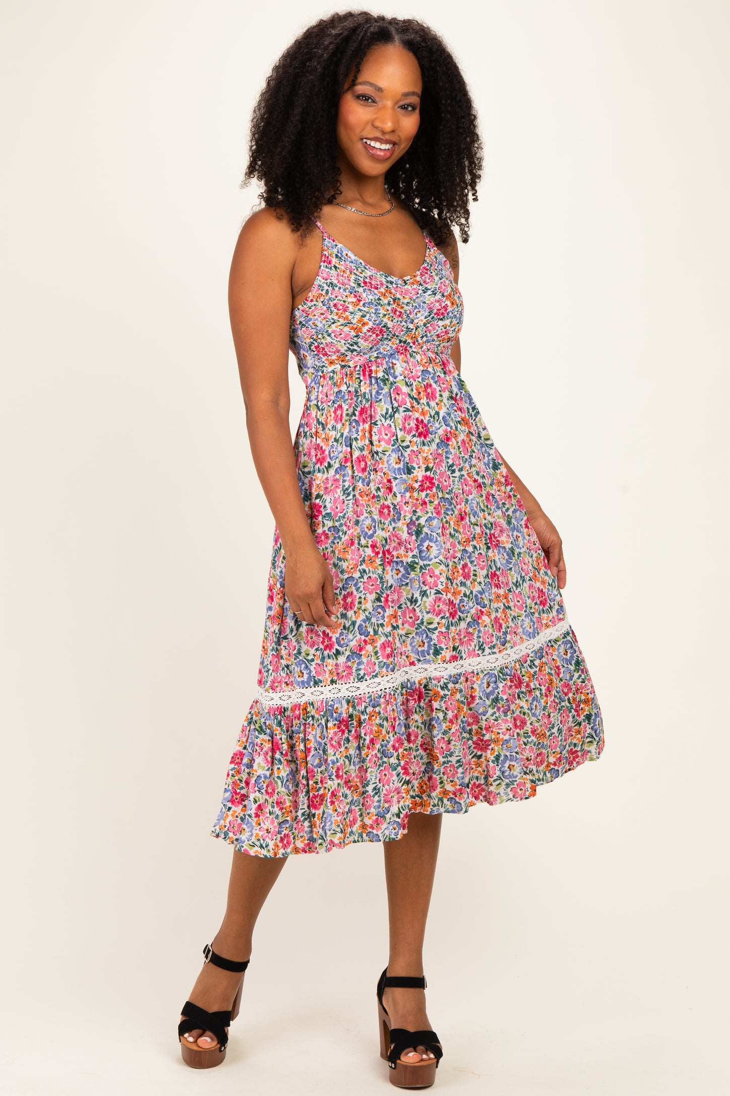 woman wearing a floral print maxi dress with a ruffled hem and spaghetti straps, standing on a neutral background
