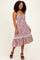 woman wearing a floral print maxi dress with a ruffled hem and spaghetti straps, standing on a neutral background