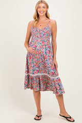 woman wearing a floral maternity dress with a smocked bodice and tiered skirt, holding her baby bump