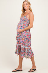 woman wearing a floral print maternity dress with a smocked bodice and ruffled hem, showcasing her baby bump
