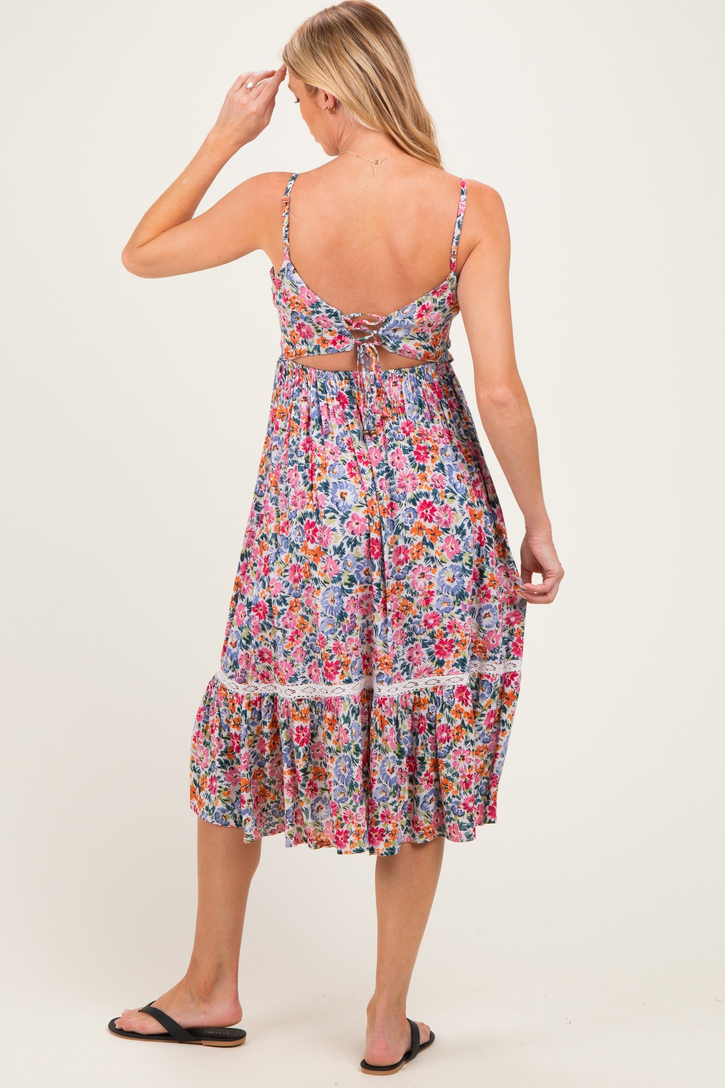 woman wearing a floral open-back maternity dress with a tiered skirt and adjustable straps
