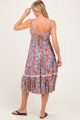 woman wearing a floral open-back maternity dress with a tiered skirt and adjustable straps