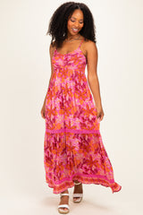 woman wearing a vibrant pink floral maxi dress with spaghetti straps and tiered skirt, smiling and standing on a plain background