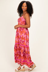 woman wearing a pink floral maxi dress with a tiered skirt and spaghetti straps, standing sideways with curly hair