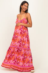 woman wearing a pink floral maternity maxi dress and holding her baby bump