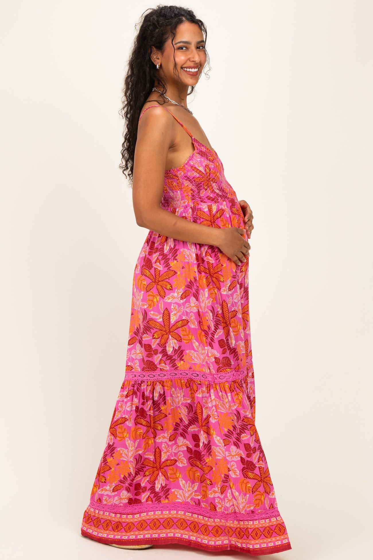 woman wearing a pink floral maternity maxi dress and holding her baby bump