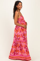 woman wearing a pink floral maternity maxi dress and holding her baby bump