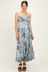 woman wearing a floral print maternity maxi dress with spaghetti straps and a flowing hem, showing her baby bump