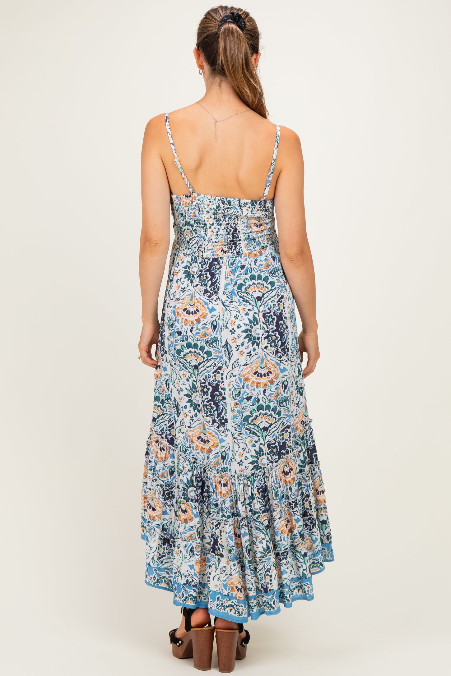 woman wearing a floral print maternity maxi dress with a smocked bodice and back, featuring a tiered skirt