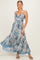 woman wearing a blue and white floral maxi dress with adjustable straps and a flowing skirt