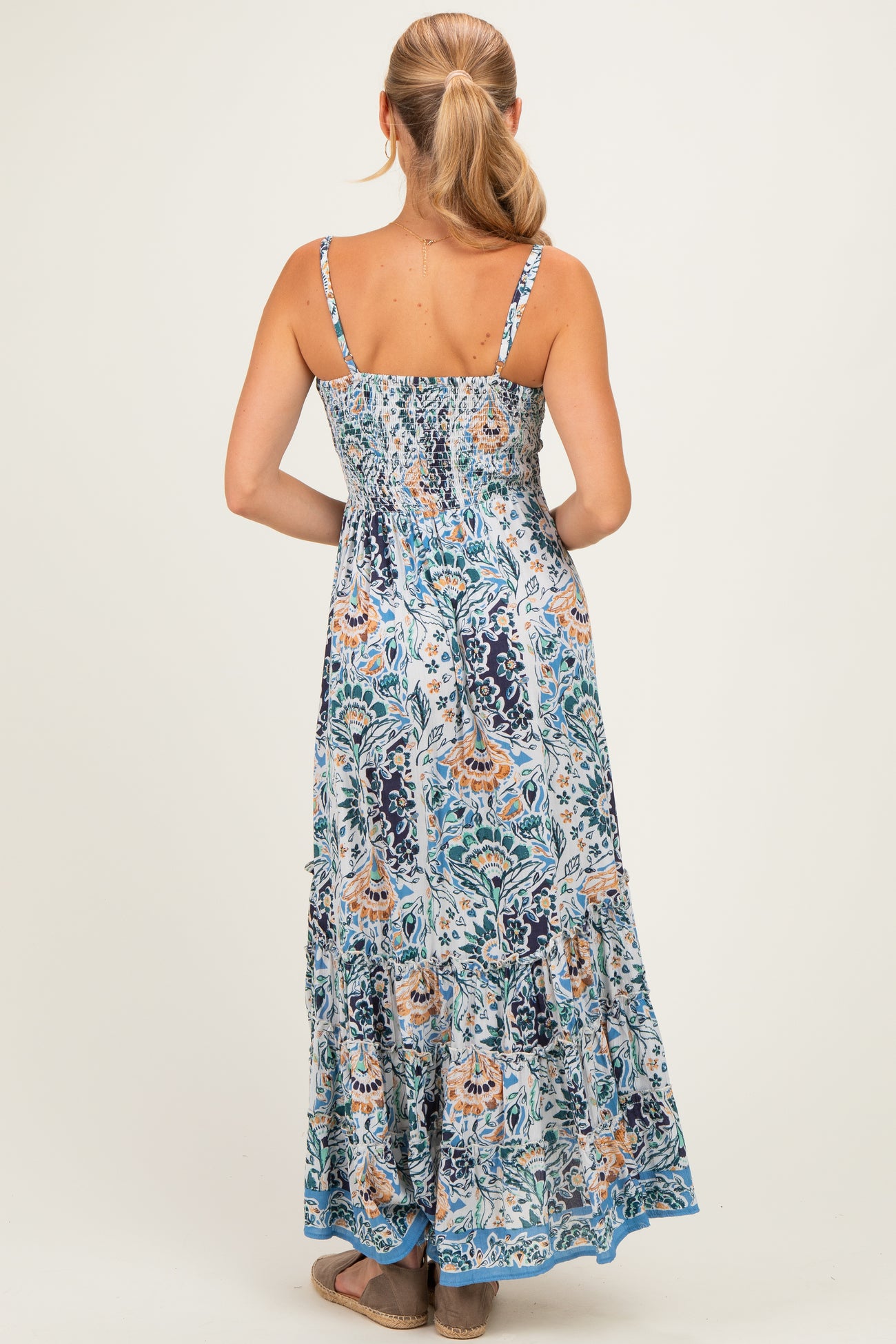 woman wearing a floral print maxi dress with a smocked bodice and tiered skirt, showing the back view