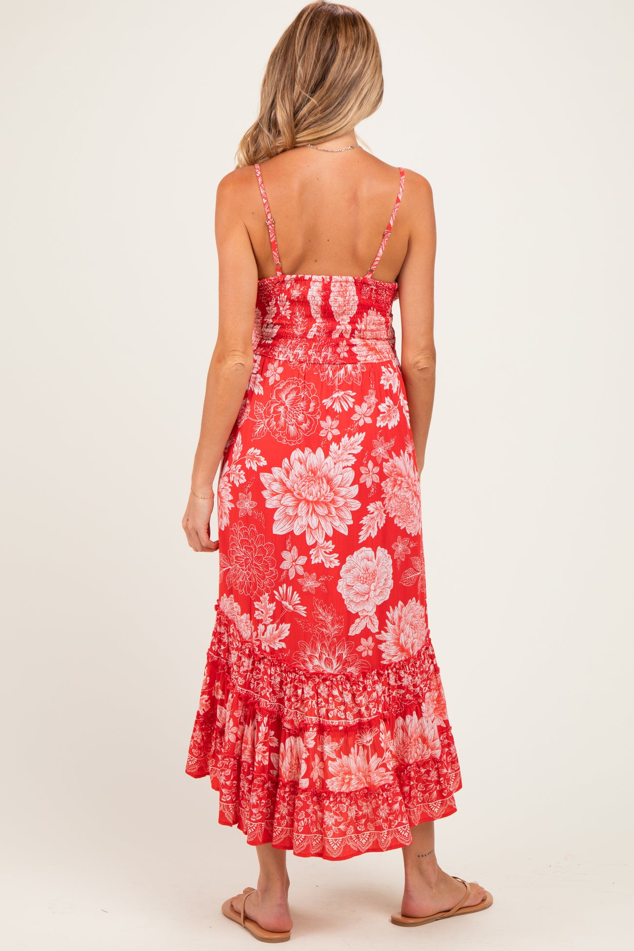 woman wearing a red floral maternity maxi dress with spaghetti straps and a ruffled hemline