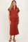 woman wearing a rust-colored maternity midi dress with a collar and side slits, showcasing her baby bump
